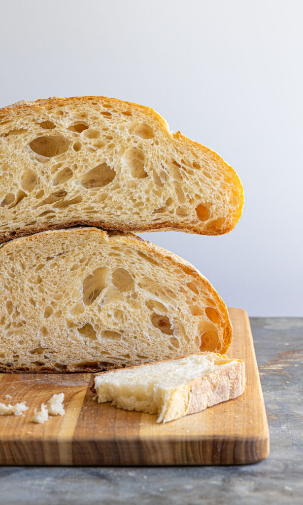 paesano bread loaf cut in half and stacked on a cutting board